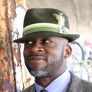 A dark-skinned man with green brimmed hat.