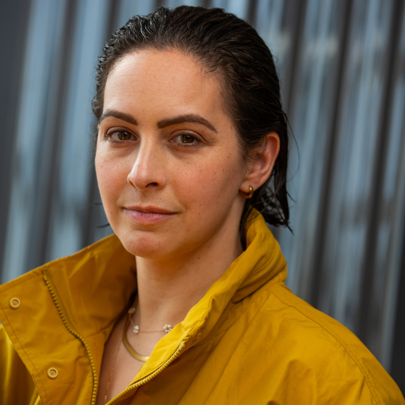 Headshot of an individual in a yellow coat with a high collar.